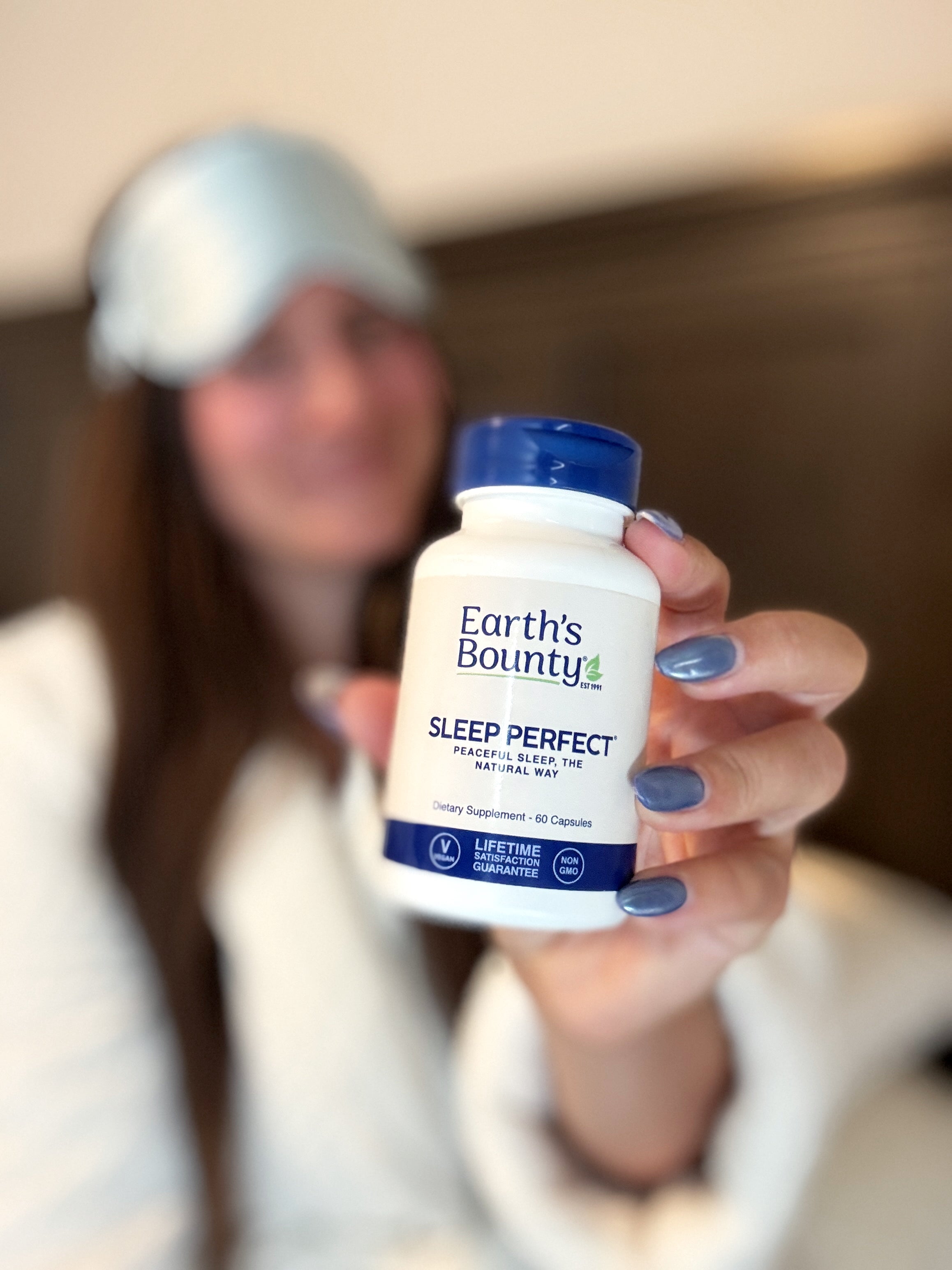 Person holding a bottle of Earth's Bounty Sleep Perfect supplement with a blurred background